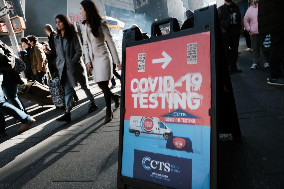 People walk by groups of people lined-up to get tested for COVID-19 in Times Square in New York City. With the newly discovered omicron variant, health officials are urging people to get vaccinated.