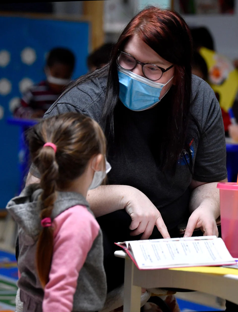 Sammie Boatright, a teacher for 3-year-olds at Small World of Learning day care in Abilene, Texas, assists a student in reading a book Tuesday.