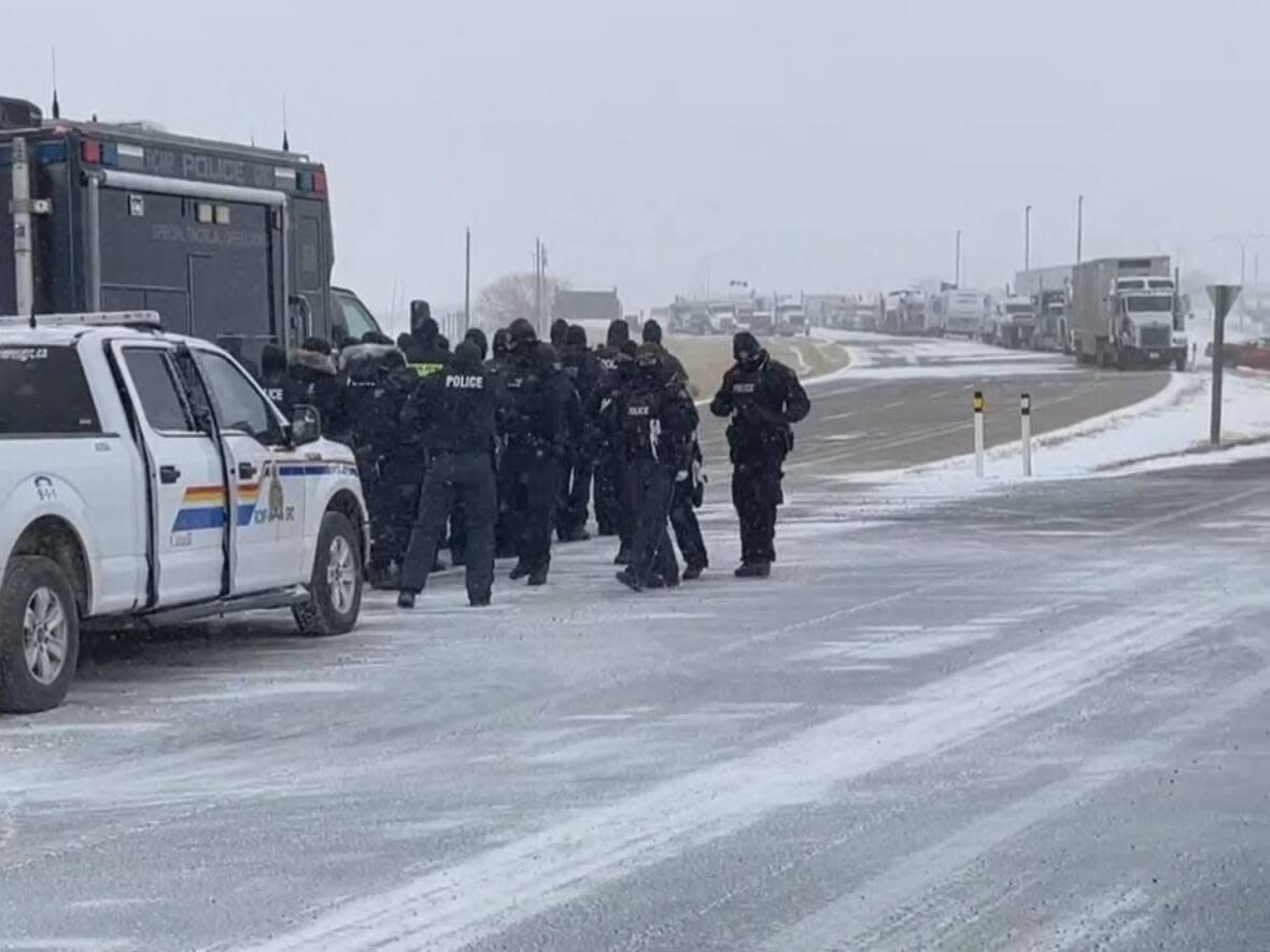 Law enforcement prepares to approach a line of vehicles blocking a Canada-U.S. border crossing in southern Alberta in February during protests at the Coutts crossing. (David Rae/CBC - image credit)