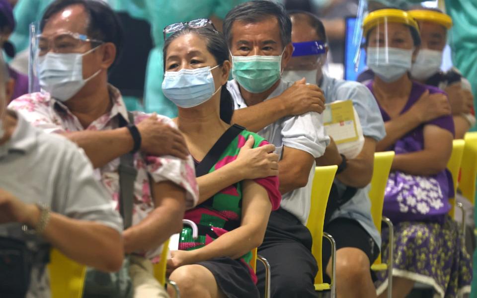 People rest after receiving a dose of the Moderna vaccine at an exhibition hall in Taipei City - Reuters