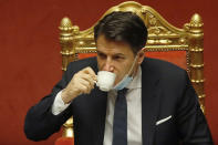 FILE - In this Tuesday, Jan. 19, 2021 file photo, Italian premier Giuseppe Conte sips a coffee during a debate at the Senate prior to a confidence vote, in Rome. When Giuseppe Conte exited the premier’s office, palace employees warmly applauded in him appreciation. But that’s hardly likely to be Conte’s last hurrah in politics. Just a few hours after the handover-ceremony to transfer power to Mario Draghi, the former European Central Bank chief now tasked with leading Italy in the pandemic, Conte dashed off a thank-you note to citizens that sounded more like an ’’arrivederci″ (see you again) then a retreat from the political world he was unexpectedly propelled into in 2018. (AP Photo/Alessandra Tarantino, Pool)