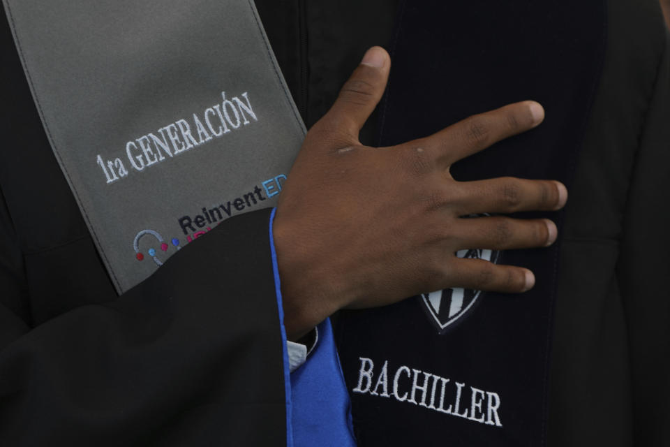 A high school senior takes the graduates' oath during his graduation ceremony at the Reinvented IDV school run by Independence del Valle club in Quito, Ecuador, Thursday, Aug. 18, 2022. The club trains young men in soccer while providing them with up to a high school graduation and has become a key source for the country’s national soccer team. (AP Photo/Dolores Ochoa)