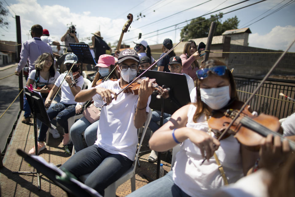 Con mascarillas para frenar la propagación del nuevo coronavirus, los músicos se unen al pianista, compositor y director José Agustín Sánchez en la plataforma de un camión de dieciocho ruedas para una gira musical llamada "Desinfección musical", en Barquisimeto, Venezuela, el jueves 4 de marzo. 2021. Sánchez, quien el año pasado comenzó a tocar lo que él llama su "Vacuna Musical" para pacientes con COVID, ahora se une a otros músicos mientras recorren la ciudad tocando sus composiciones originales para cualquiera que quiera escuchar. (AP Foto/Ariana Cubillos)