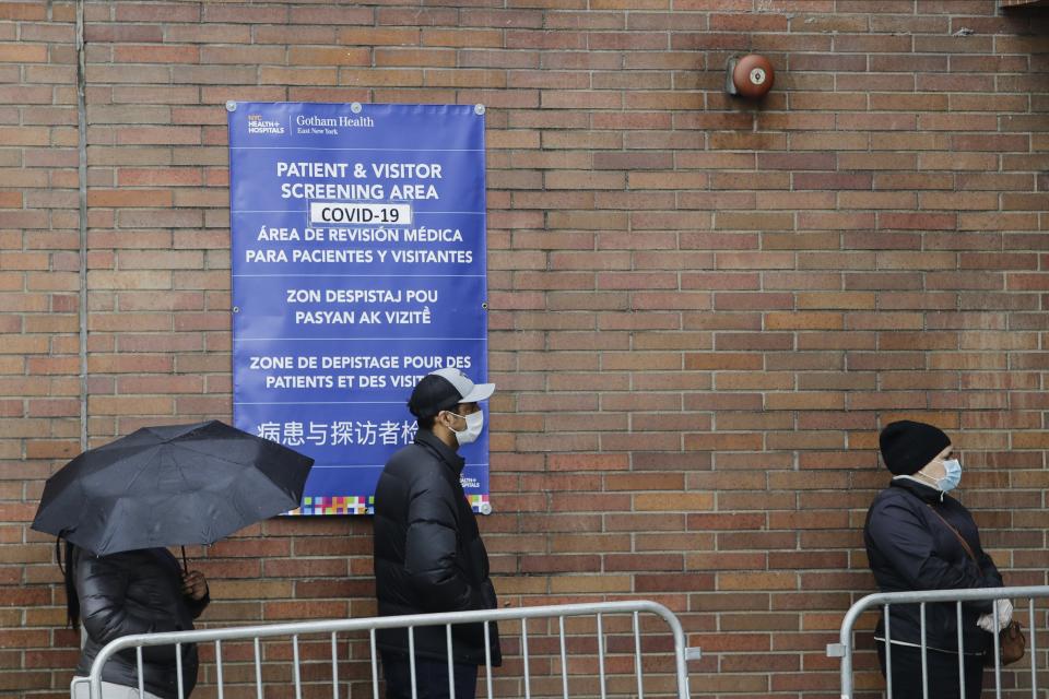 People wearing personal protective equipment line up to be screened for COVID-19 at Gotham Health East New York, Thursday, April 23, 2020, in the Brooklyn borough of New York. (AP Photo/Frank Franklin II)