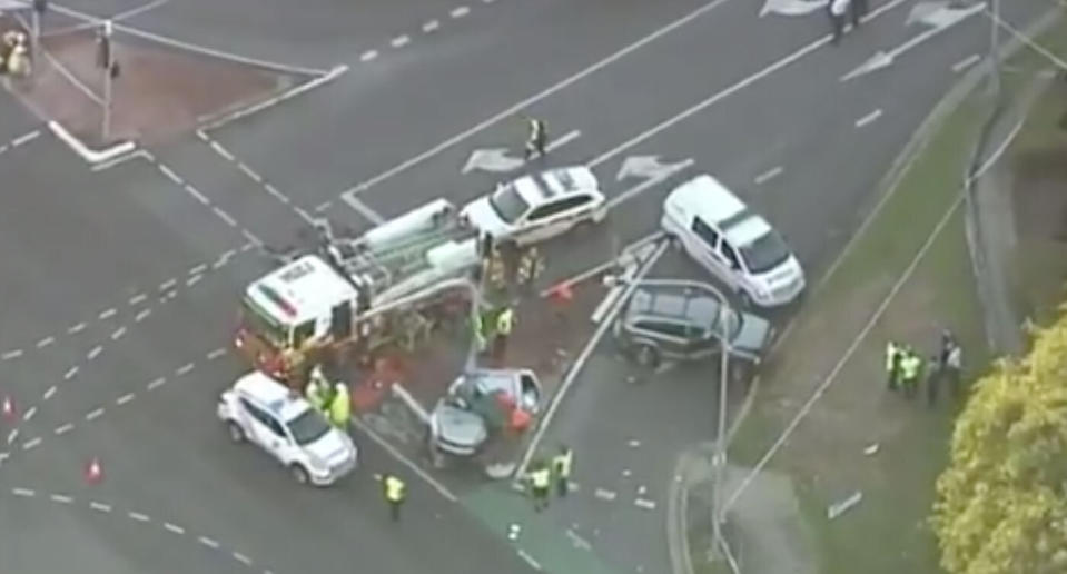 Pictured is the crash scene at Rothwell. A car is seen smashed next to a light pole with police and fire fighters investigating.