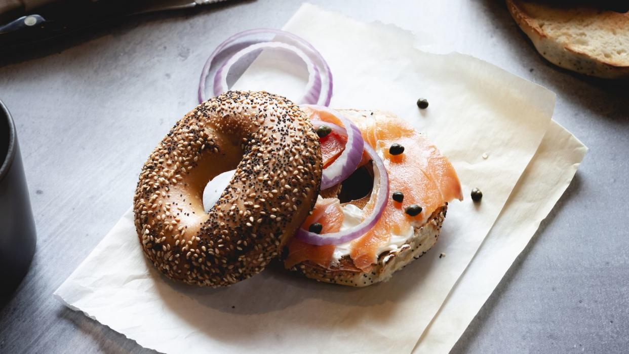 close up of lox bagel with onions on paper sheet