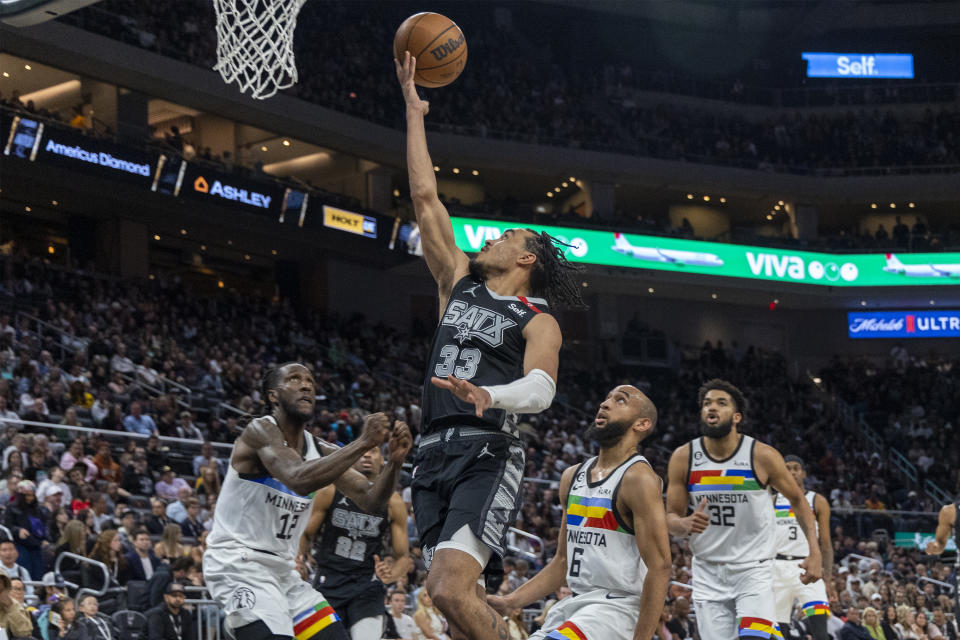 San Antonio Spurs guard Tre Jones (33) goes to the basket between Minnesota Timberwolves forward Taurean Prince (12) and guard Jordan McLaughlin (6) during the second half of an NBA basketball game, Saturday, April 8, 2023, in Austin, Texas. (AP Photo/Stephen Spillman)