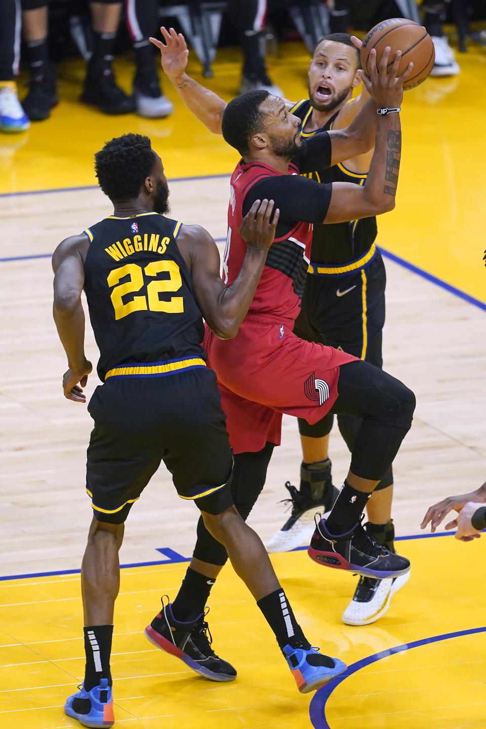 Portland Trail Blazers forward Norman Powell, middle, shoots between Golden State Warriors forward Andrew Wiggins (22) and guard Stephen Curry during the first half of an NBA basketball game in San Francisco, Wednesday, Dec. 8, 2021. (AP Photo/Jeff Chiu)