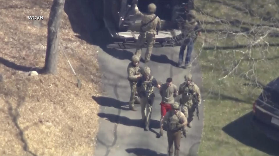 This image made from video provided by WCVB-TV, shows Jack Teixeira, in T-shirt and shorts, being taken into custody by armed tactical agents on Thursday, April 13, 2023, in Dighton, Mass. (WCVB-TV via AP)