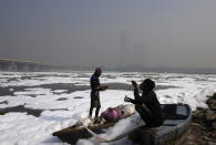 <p>A person eats snack sitting on his boat in the Yamuna River, covered by a chemical foam caused by industrial and domestic pollution amidst toxic smog in New Delhi, India, Wednesday, Nov. 17, 2021. Schools were closed indefinitely and some coal-based power plants shut down as the Indian capital and neighboring states invoked harsh measures Wednesday to combat air pollution after an order from the federal environment ministry panel. (AP Photo/Manish Swarup)</p> 