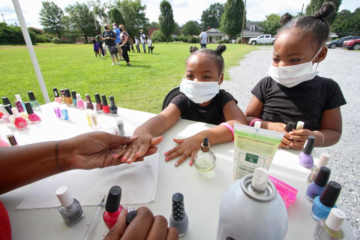 Four-year-old twins  Kennedy and Khloe Clemmons get their nails painted during the Backpack Giveaway held Saturday, Aug. 22, 2020, at Changers Church on Hudson Street in Shelby.