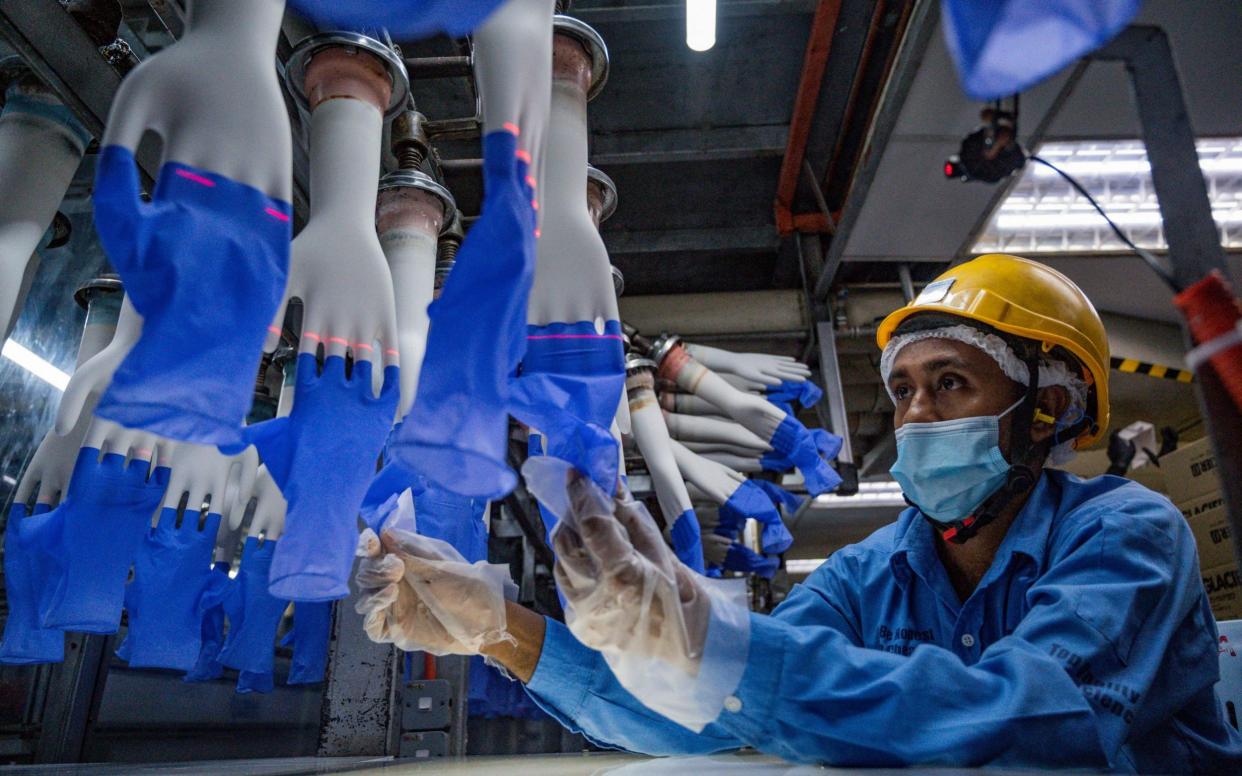 a worker inspects disposable gloves at the Top Glove factory in Shah Alam on the outskirts of Kuala Lumpur - AFP