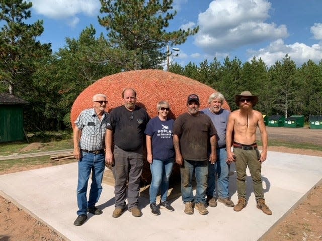 Terri Nelson, center, stands with volunteers from Lake City Towing and Walt Moss Trucking, who teamed up to move James Frank Kotera's giant ball of twine from his property to a spot on town of Highland land where people can visit it.