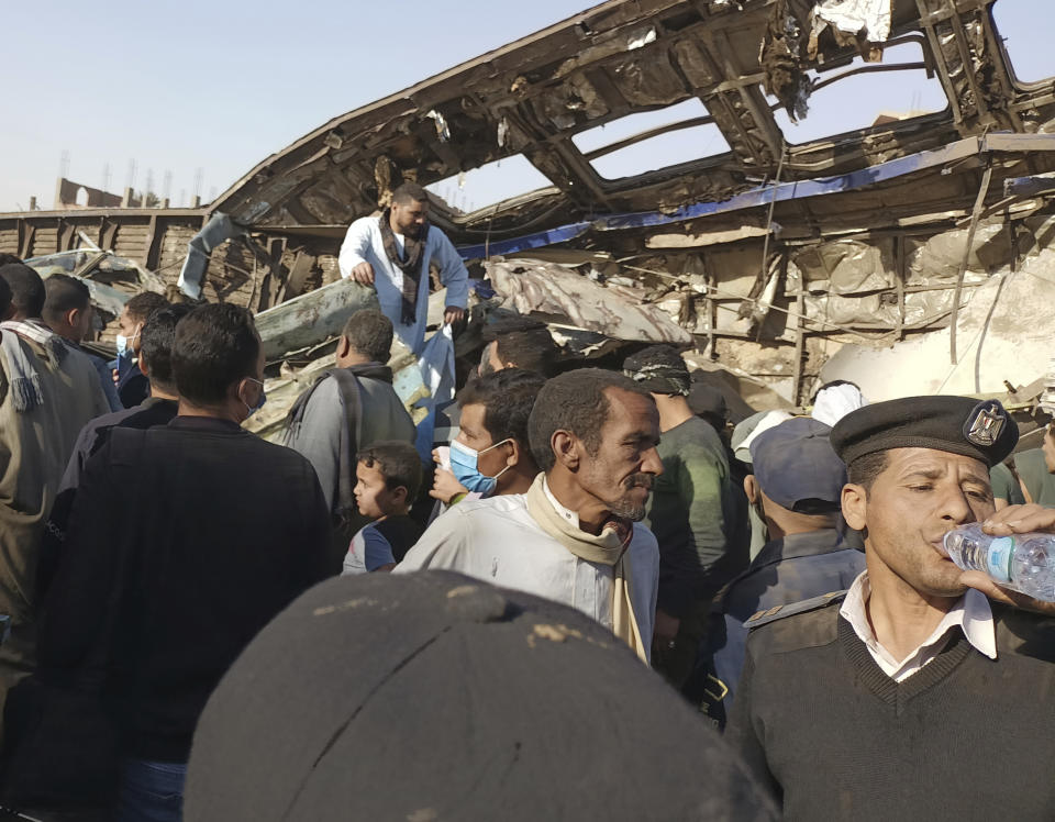 An Egyptian policeman drinks water as villagers look for remains of victims around mangled train carriages at the scene of a train accident in Sohag,Egypt, Friday, March 26, 2021. Egyptian officials say two trains collided in southern Egypt in the latest in a series of deadly accidents along Egypt's troubled rail system, which has been plagued by poor maintenance and management. (AP Photo)