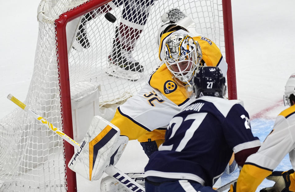 Colorado Avalanche left wing Jonathan Drouin (27) lifts puck over the shoulder of Nashville Predators goaltender Kevin Lankinen for a goal in the first period of an NHL hockey game Saturday, March 30, 2024, in Denver. (AP Photo/David Zalubowski)