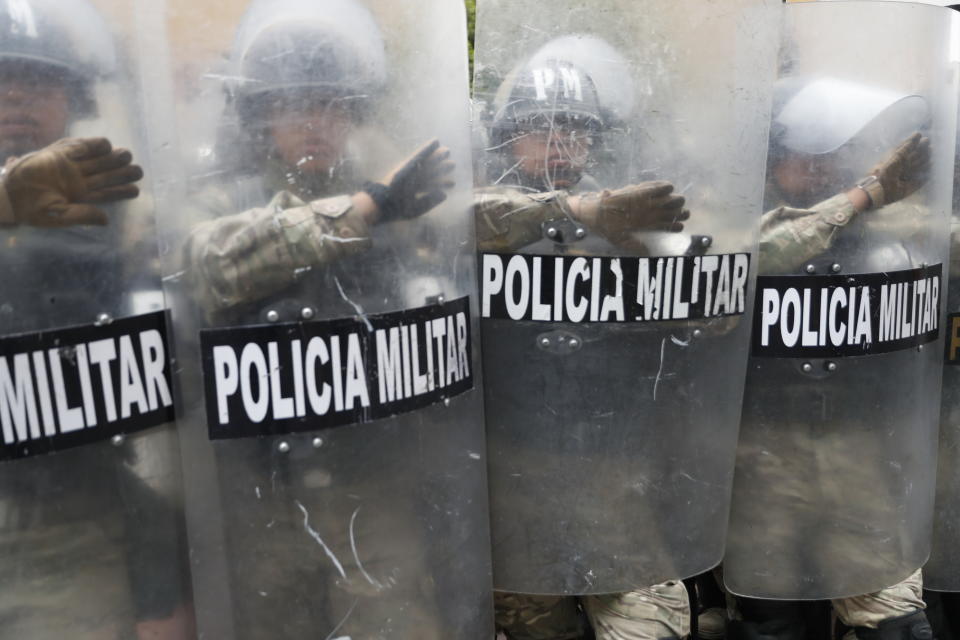 Police take cover behind their shields during a march of supporters of former President Evo Morales in La Paz, Bolivia, Thursday, Nov. 14, 2019. Morales resigned and flew to Mexico under military pressure following massive nationwide protests over alleged fraud in an election last month in which he claimed to have won a fourth term in office. (AP Photo/Natacha Pisarenko)