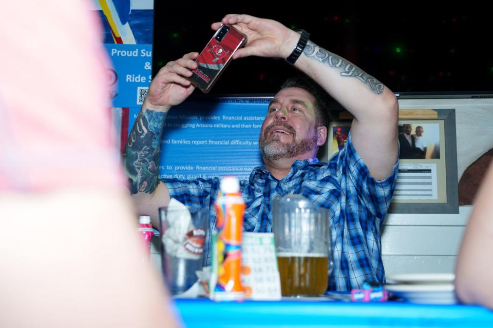 Boomer Nichols takes out his phone to record as his daughter hosts drag bingo alongside well-known drag queen Barbra Seville at Playa II in Phoenix on Aug. 26, 2023.