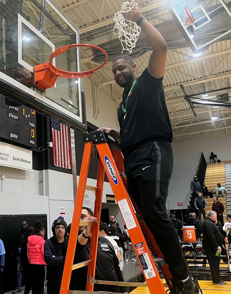 First-year Worthington Christian coach Quintin Aden holds up the net as his team celebrates winning a Division III district title Thursday at Ohio Dominican.