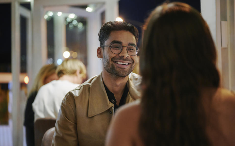 A man and woman sit across from each other at a cozy restaurant, smiling and talking, creating a warm and intimate atmosphere