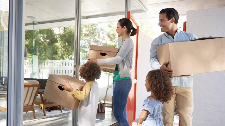 Shot of a young family moving into a new house with boxes in their hands.