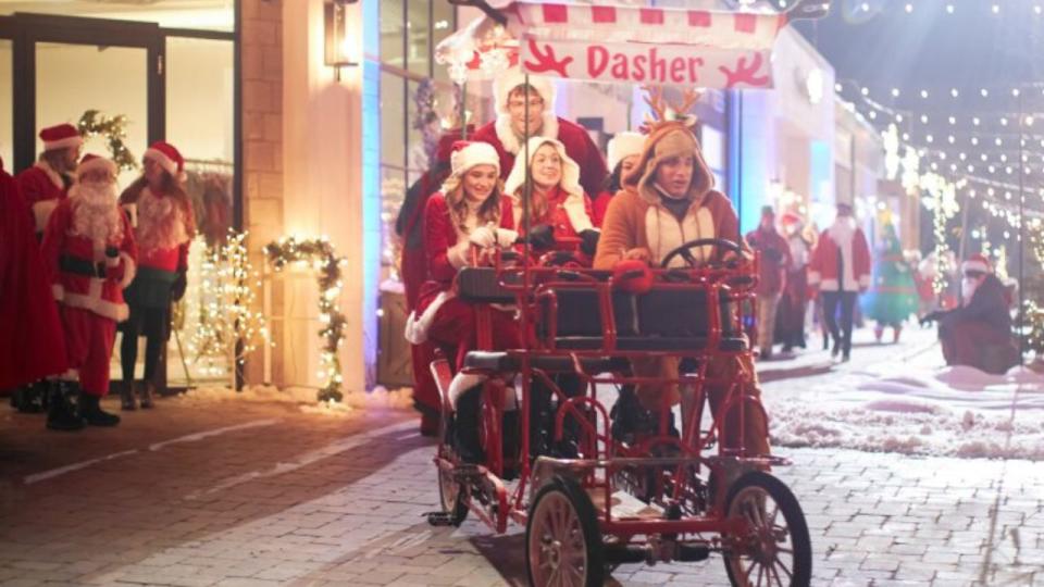 The stars of The Santa Summit riding a bike wagon