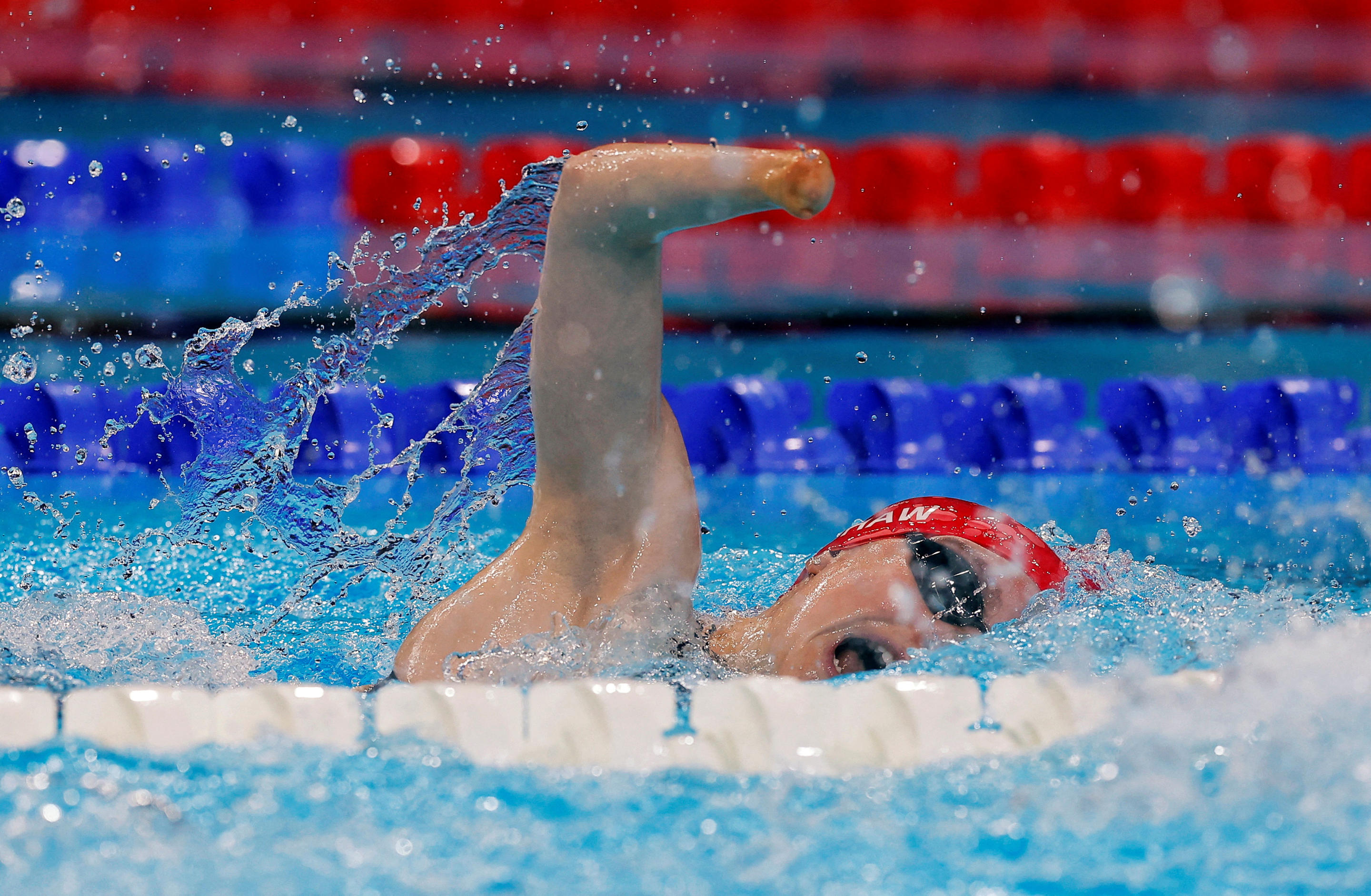 A woman wearing a red bathing cap in a swimming pool.