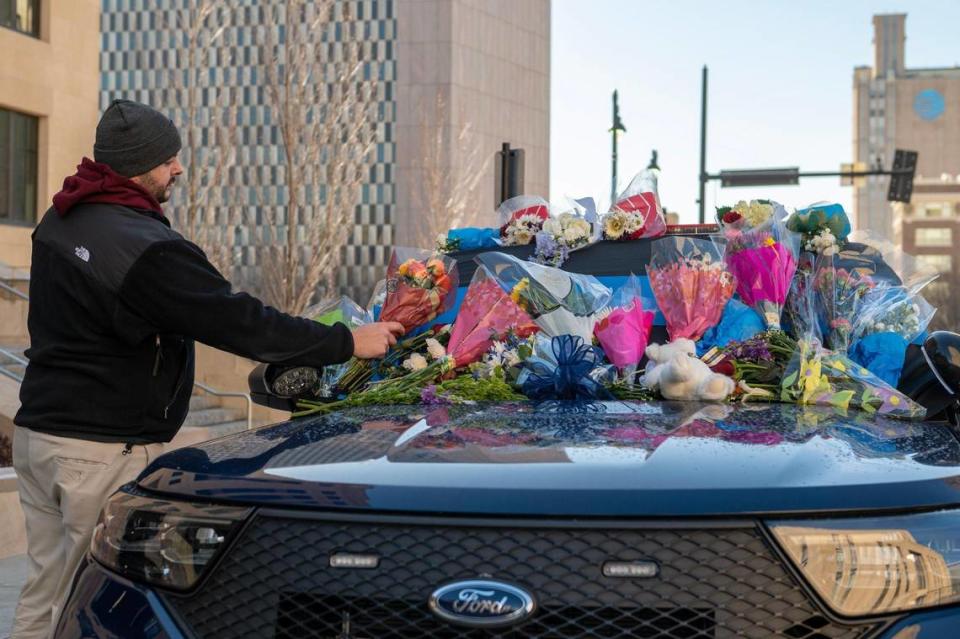 Tyler Colbert, a friend of Kansas City Police Officer James Muhlbauer, places flowers on a patrol car at KCPD Headquarters on Friday, Feb. 17, 2023. Muhlbauer and his K-9 police dog Champ were killed in a car crash Wednesday when a vehicle struck their patrol car. A pedestrian was also killed in the crash.