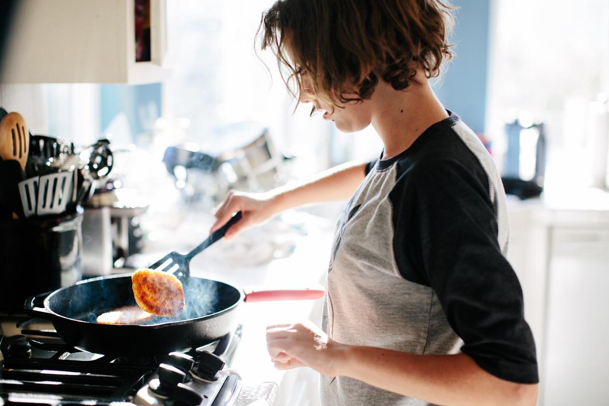 Woman flips a steaming hash brown in a cast iron pan