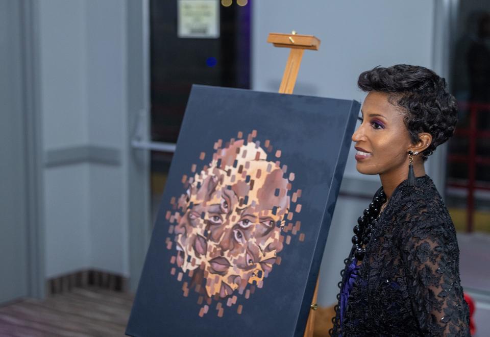 Faith Green poses next to the painting illustrated by 21-year old Detroit native Kirah Price at  nonprofit organization How Understanding Something Helps (H.U.S.H.) "Painting My Pain" event at the Riverside Marina in Detroit.