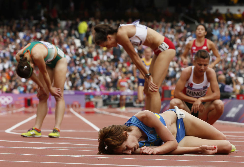 Ukraine's Valentyna Horpynych Zhudina (C) lies on the track as other athletes recover after their women's 3000m steeplechase round 1 heats at the London 2012 Olympic Games at the Olympic Stadium August 4, 2012. REUTERS/Lucy Nicholson (BRITAIN - Tags: OLYMPICS SPORT ATHLETICS TPX IMAGES OF THE DAY) 