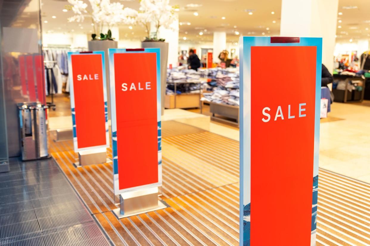 Red bright sale banner on anti-thieft gate sensor at retail shopping mall entrance. Seasonal discount offer in store.