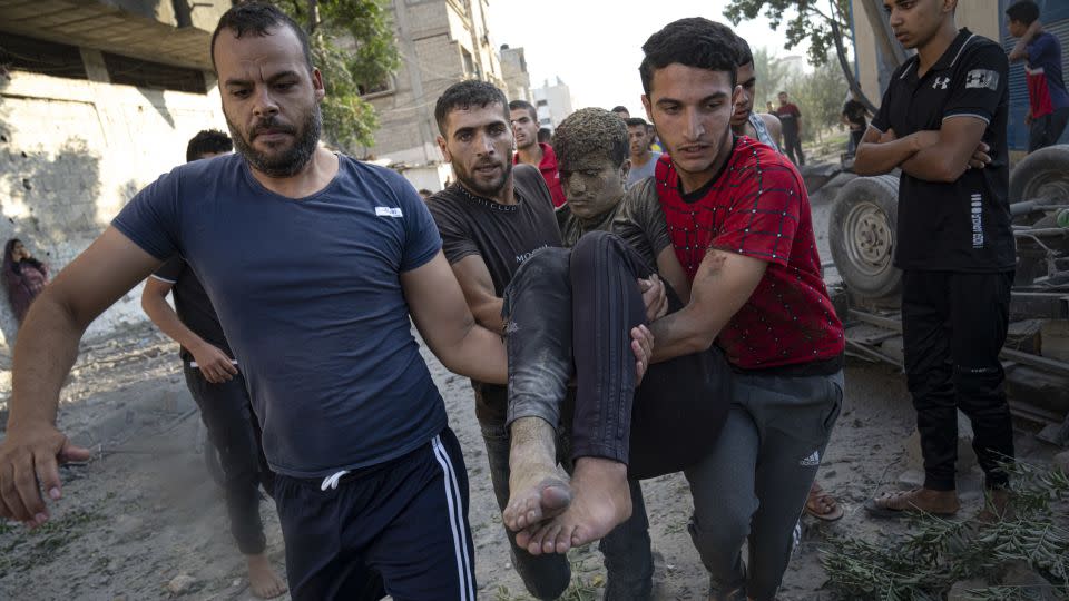 Palestinians carry a person wounded in Israeli airstrikes in Khan Younis, Gaza, on October 16. - Fatima Shbair/AP