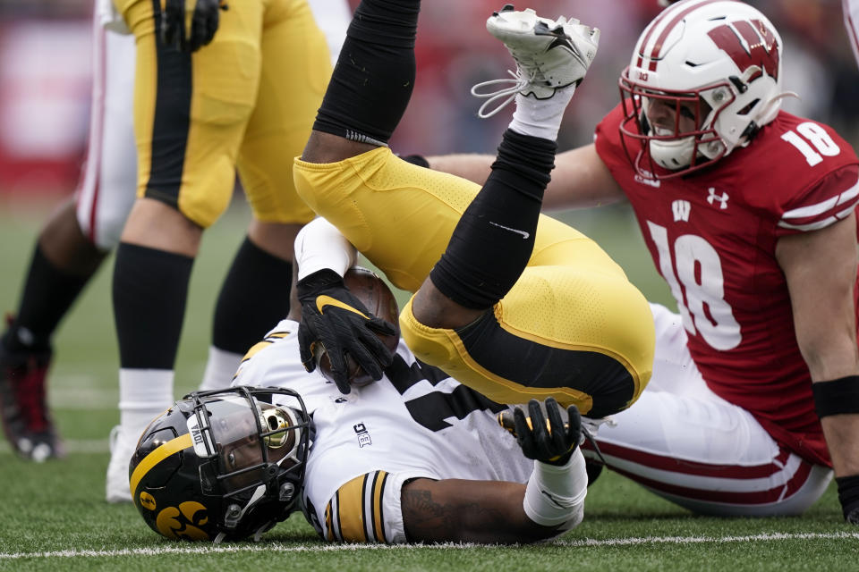 FILE - Wisconsin safety Collin Wilder (18) stops Iowa running back Tyler Goodson (15) during the first half of an NCAA college football game Saturday, Oct. 30, 2021, in Madison, Wis. Across the country, college football teams once again are discovering that establishing a rushing attack is even tougher than it was the year before. Nowhere is this trend more apparent than at No. 20 Wisconsin. (AP Photo/Andy Manis, File)