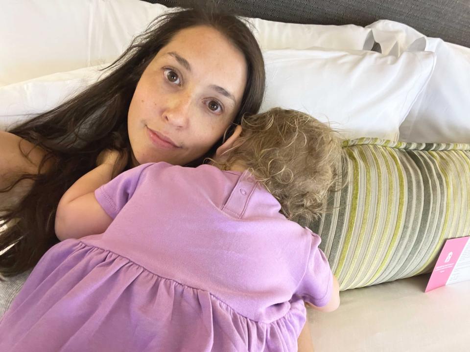 A toddler girl asleep on her mother while she takes a selfie.