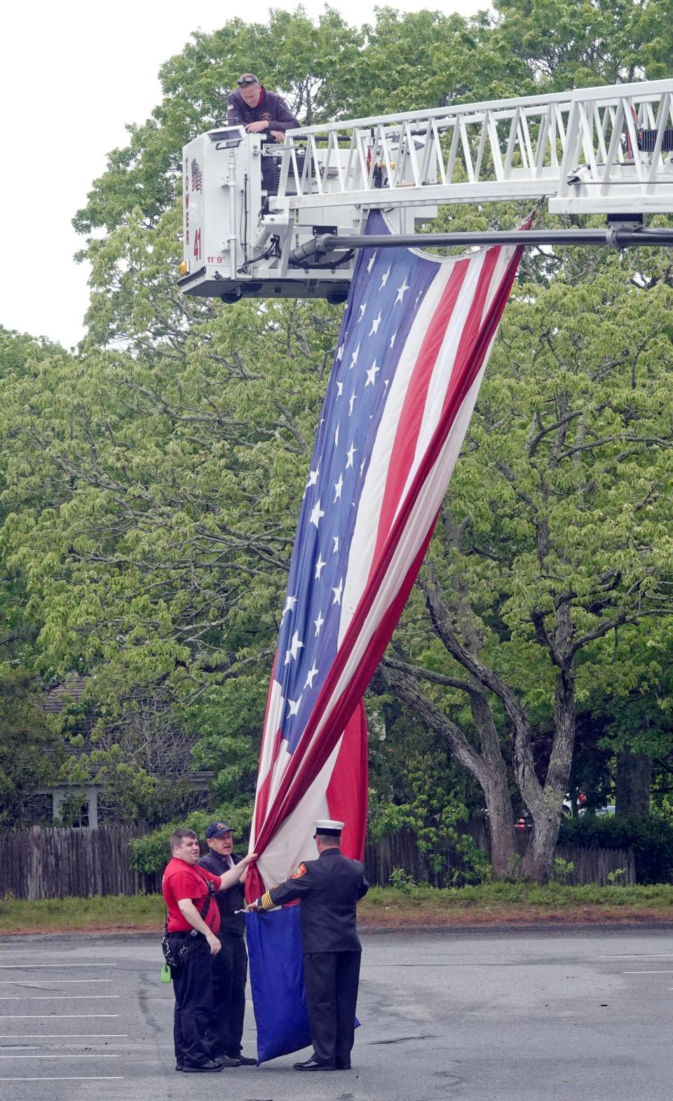 Yarmouth fire personnel take down the large flag that had been draped from the department's ladder truck during the Memorial Day parade last year at town hall.