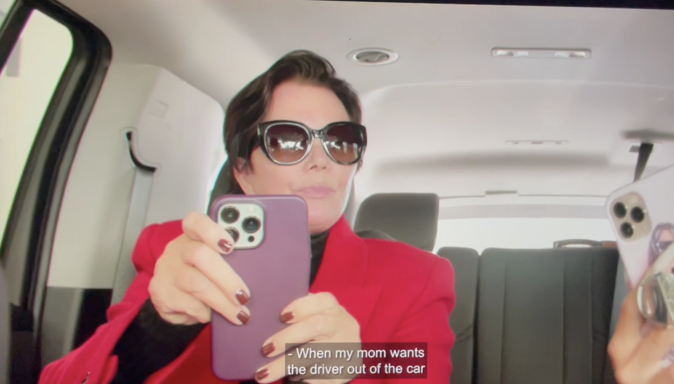 Kris Jenner holding her cellphone in the back of the car.