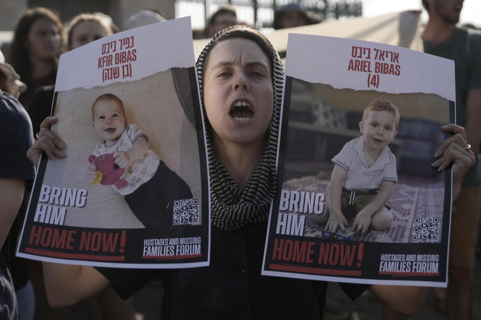 A woman holds posters of Kfir and Ariel Bibas, who are in Hamas captivity with their parents in the Gaza Strip, as students march towards The Knesset, Israel's parliament, to call for a deal to release hostages, in Jerusalem, Thursday, June 13, 2024. (AP Photo/Mahmoud Illean)