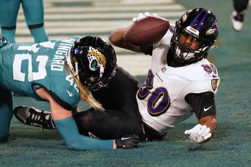 Baltimore Ravens tight end Isaiah Likely (80) catches a touchdown pass as he is defended by Jacksonville Jaguars safety Andrew Wingard (42) in the first half of an NFL football game Sunday, Dec. 17, 2023, in Jacksonville, Fla. (AP Photo/John Raoux)
