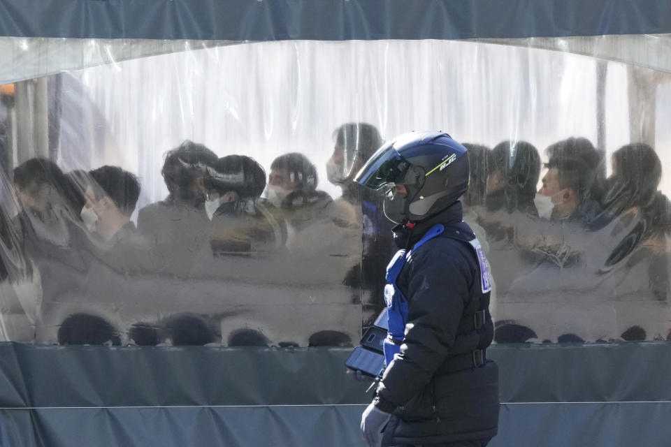 A person wearing a motorcycle helmet and a face mask passes by a makeshift testing site in Seoul, South Korea, Friday, Jan. 28, 2022. (AP Photo/Ahn Young-joon)