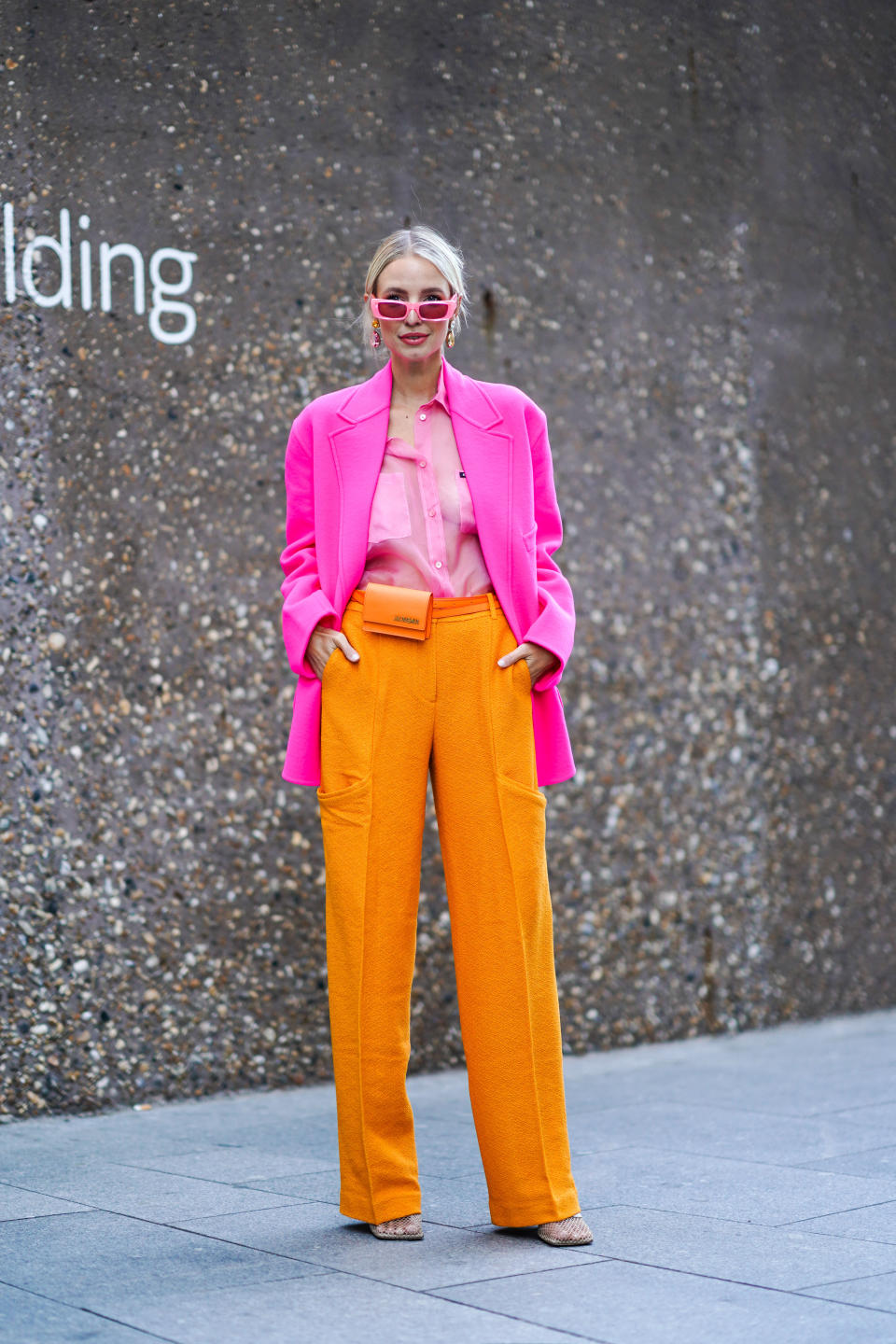 Leonie Hanne is seen wearing a pair of pink sunglasses, earrings, a pink blazer jacket, a pink shirt, orange flare trousers and an orange Jacquemus belt bag. <a href="https://fave.co/31nhXgo" rel="noopener" target="_blank" data-ylk="slk:Shop the bag here;elm:context_link;itc:0;sec:content-canvas" class="link ">Shop the bag here</a>. [Photo: Getty Images]