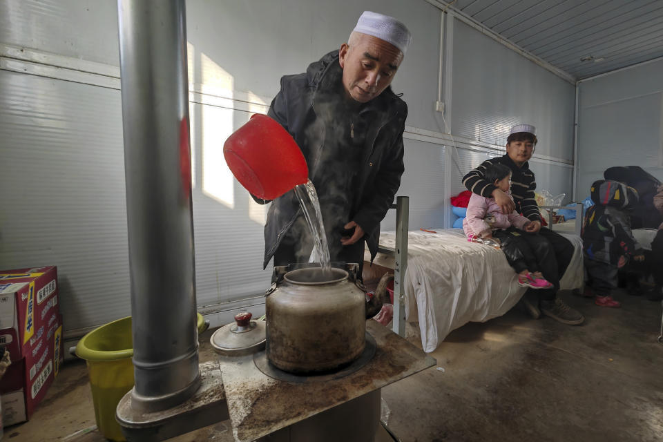 In this photo released by Xinhua News Agency, a resident boils water inside a movable plank houses set up for earthquake victims in Meipo Village, Jishishan County in northwest China's Gansu Province, Thursday, Dec. 21, 2023. Hundreds of temporary one-room housing units were being set up Thursday in northwest China for survivors of an earthquake that destroyed more than 14,000 homes and killed at least 135 people, according to state media reports. (Fan Peishen/Xinhua via AP)