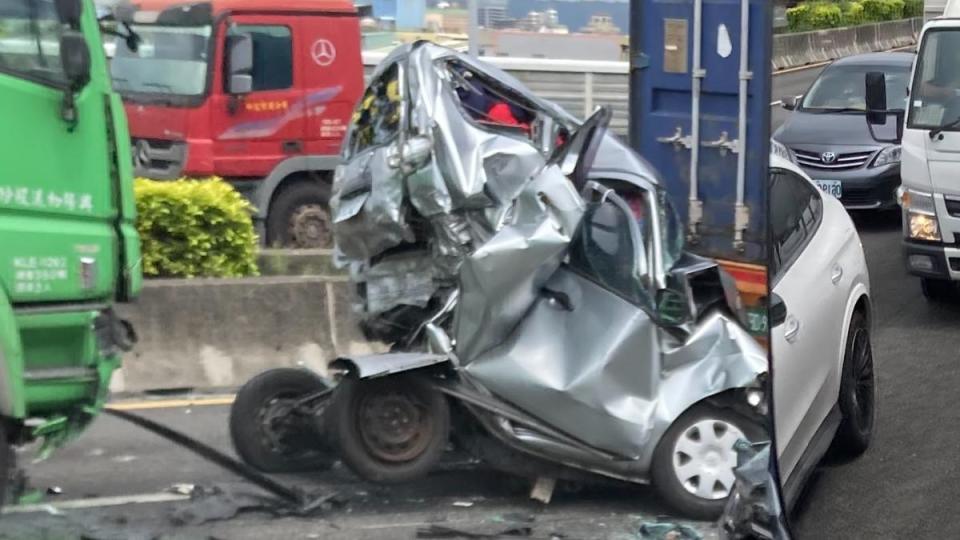 銀色轎車被壓成鐵餅，裡面二人受困失去生命跡象。（圖／翻攝自記者爆料網）