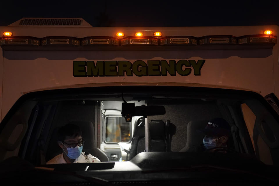 Emergency medical technicians Joshua Hammond, right, and Thomas Hoang, of Emergency Ambulance Service, sit in their ambulance after transporting a patient to an emergency room in Placentia, Calif., Friday, Jan. 8, 2021. For EMTs Thomas Hoang and Joshua Hammond, the coronavirus is constantly close. COVID-19 has become their biggest fear during 24-hour shifts in California's Orange County, riding with them from 911 call to 911 call, from patient to patient. (AP Photo/Jae C. Hong)