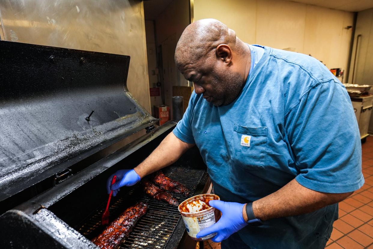 Frank Leachmon glazes ribs with sauce on the Leachmon's Pit Stop BBQ grill at Valley West Mall in West Des Moines.