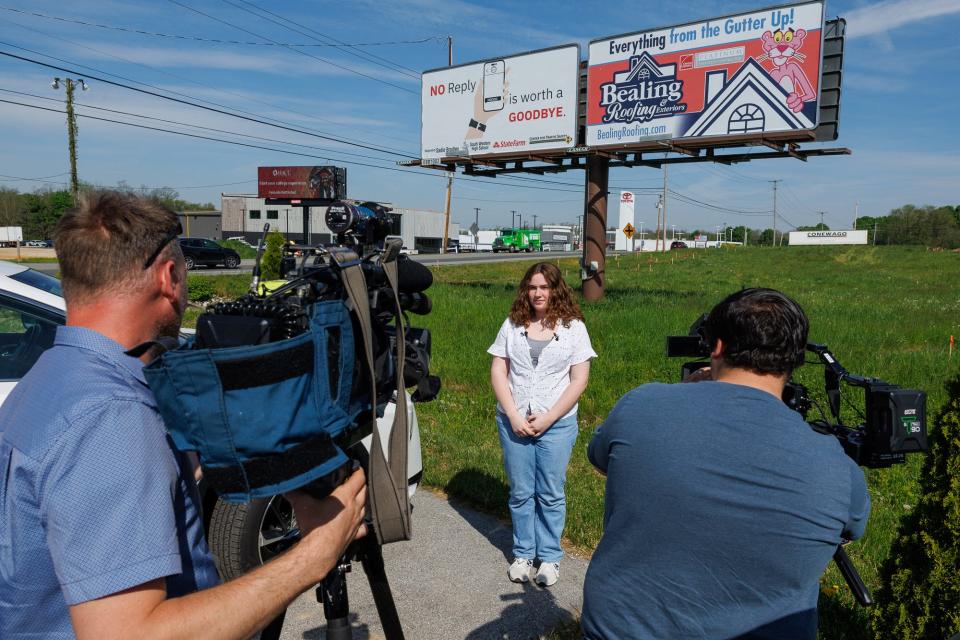Sadie Bradley, 10th grade student at South Western High School, is interviewed by TV news crews during an unveiling of her winning distracted driving billboard design along Carlisle Pike, Tuesday, April 30, 2024, in Hanover.