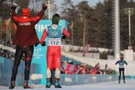 Cross-Country Skiing – Pyeongchang 2018 Winter Olympics – Men's 15km Free – Alpensia Cross-Country Skiing Centre – Pyeongchang, South Korea – February 16, 2018 - Pita Taufatofua of Tonga and Kequyen Lam of Portugal cheer for Sebastian Uprimny of Colombia to finish. REUTERS/Carlos Barria