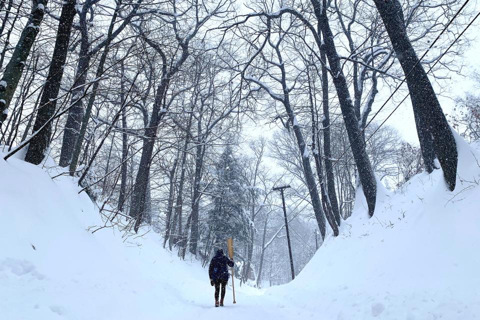 A pedestrian walks up the single plowed lane of Cascadnac Avenue in Hartford, Vermont after heavy snowfall on Thursday, Dec. 17, 2020. Parts of Vermont saw more than 20 inches of snow in the overnight storm.