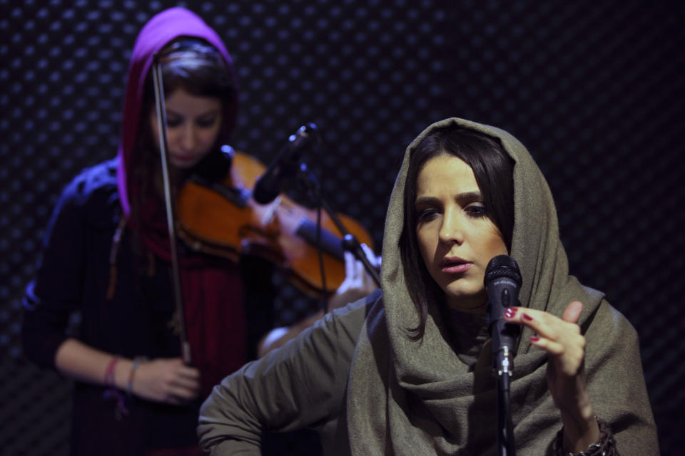 In this picture taken on Friday, Jan. 25, 2013, female Iranian back vocalist Azadeh Ettehad and violinist Nastaran Ghaffari, both members of a band called "Accolade," perform in an unauthorized stage performance in Tehran, Iran. Headphone-wearing disc jockeys mixing beats. It’s an underground music scene that is flourishing in Iran, despite government restrictions. (AP Photo/Vahid Salemi)