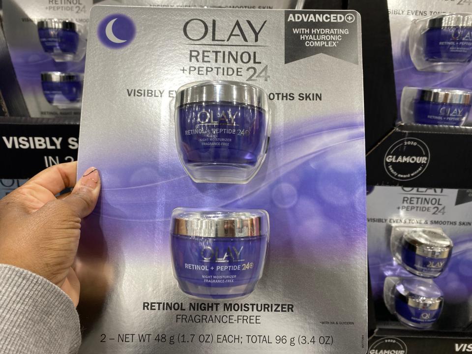 The writer holds a two-pack of Olay moisturizer with purple jars in plastic packaging