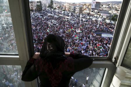 A woman stands at a window overlooking a pro-Palestinian demonstration in the northern Israeli town of Sakhnin October 13, 2015. REUTERS/Baz Ratner